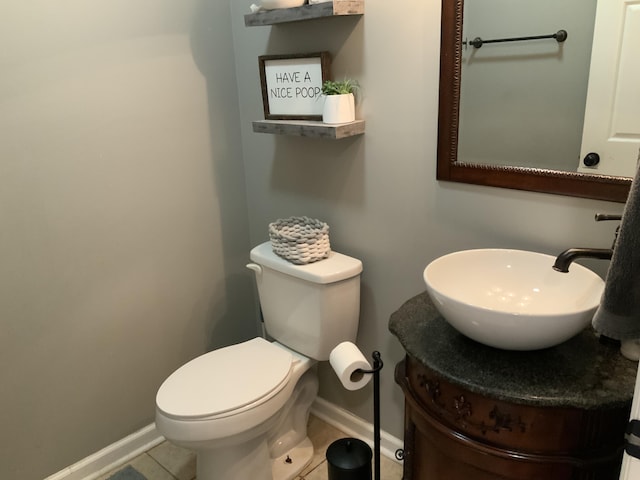 half bath with tile patterned floors, baseboards, toilet, and vanity