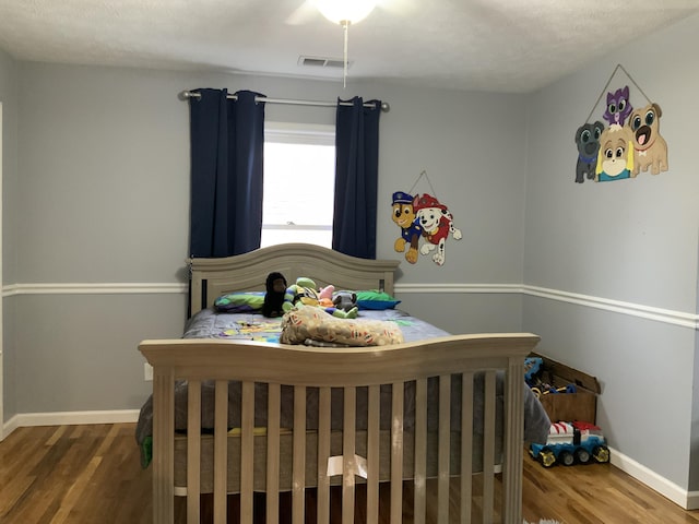 bedroom featuring visible vents, baseboards, and wood finished floors