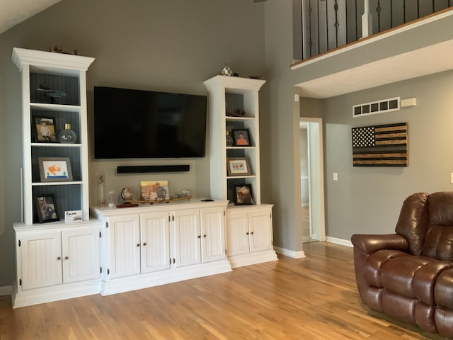 living room featuring baseboards, visible vents, and light wood finished floors