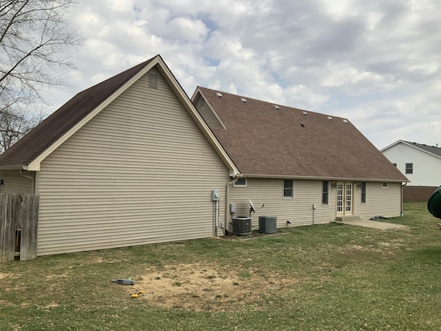 back of property featuring entry steps, a yard, central AC unit, and a shingled roof