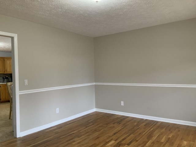 spare room featuring dark wood-type flooring and a textured ceiling