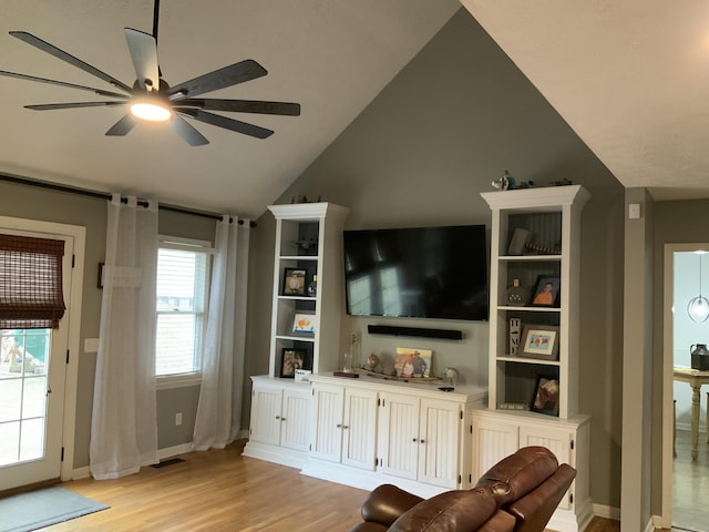 living area featuring baseboards, a ceiling fan, light wood-type flooring, and lofted ceiling