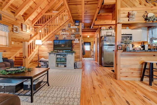 living room with beam ceiling, light hardwood / wood-style floors, wood ceiling, and wood walls