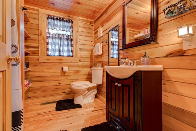 bathroom featuring wood ceiling, hardwood / wood-style flooring, vanity, toilet, and wood walls