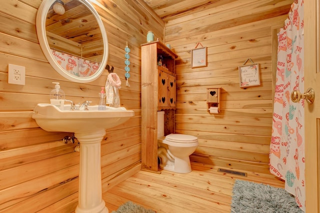 bathroom with hardwood / wood-style flooring, wood walls, and toilet