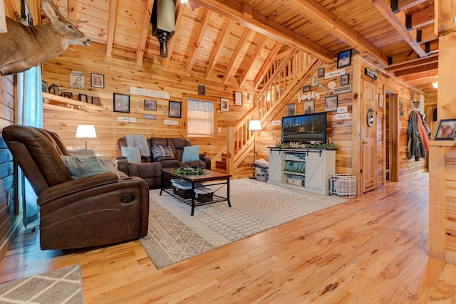 living room featuring vaulted ceiling with beams, wood ceiling, wooden walls, and light wood-type flooring