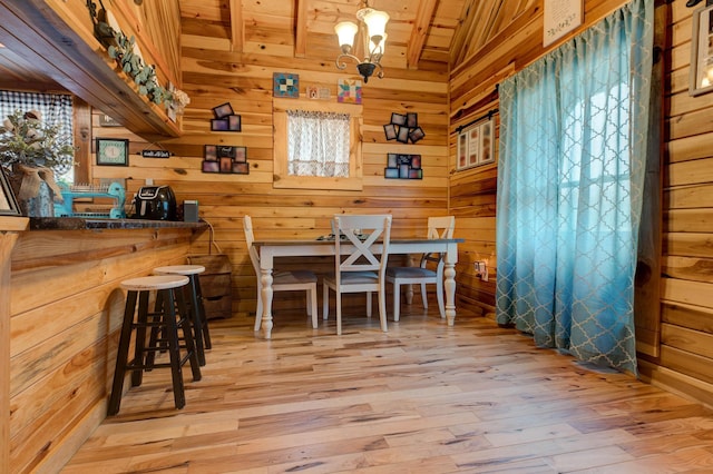 dining room with wood ceiling, wooden walls, a chandelier, and light hardwood / wood-style floors