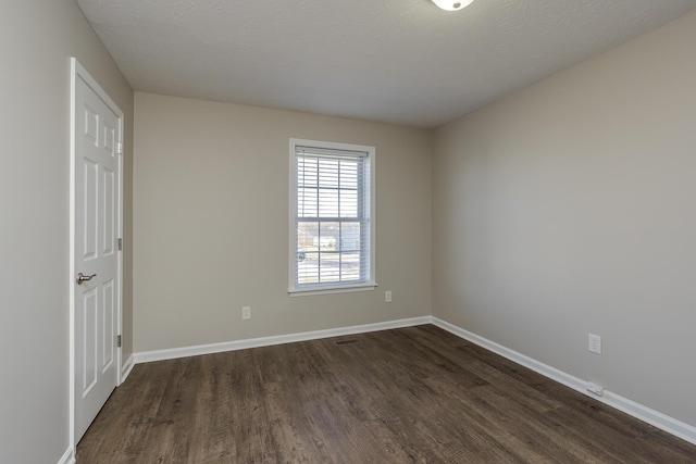 spare room featuring dark wood-type flooring and a textured ceiling