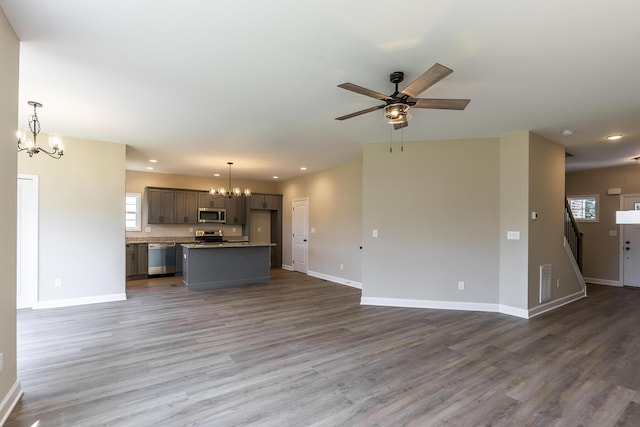 unfurnished living room featuring hardwood / wood-style flooring and ceiling fan with notable chandelier