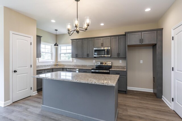 kitchen featuring sink, gray cabinetry, decorative light fixtures, appliances with stainless steel finishes, and light stone countertops