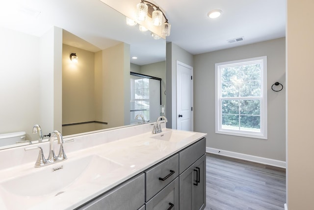 bathroom featuring hardwood / wood-style flooring, vanity, a shower with door, and toilet