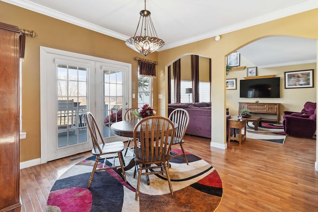 dining space featuring crown molding, an inviting chandelier, and light wood-type flooring