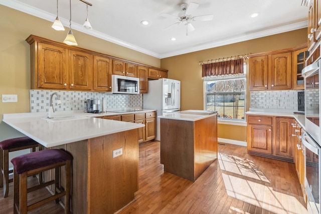 kitchen featuring a kitchen island, pendant lighting, sink, ornamental molding, and stainless steel appliances