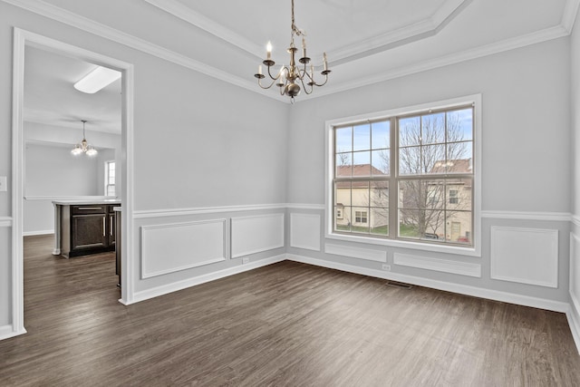 unfurnished dining area with a chandelier, a wealth of natural light, dark wood-style flooring, and a raised ceiling