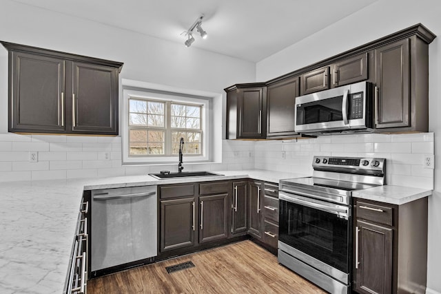 kitchen with light wood finished floors, visible vents, a sink, stainless steel appliances, and backsplash