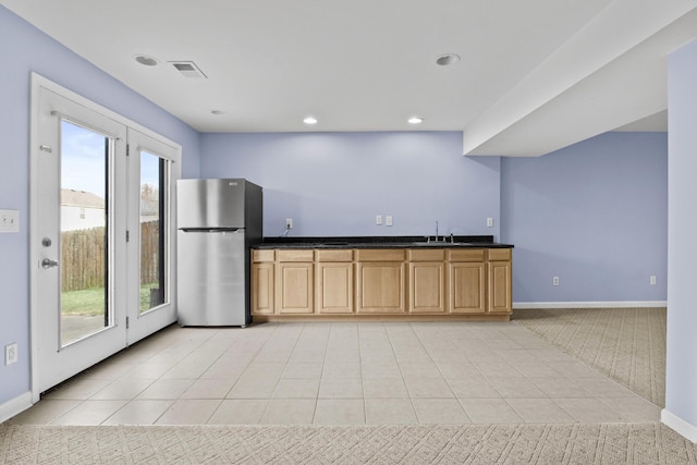 kitchen featuring light tile patterned floors, visible vents, baseboards, freestanding refrigerator, and dark countertops