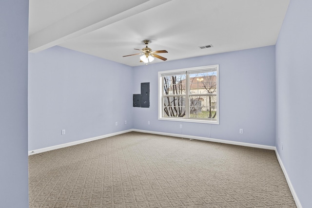 carpeted empty room with electric panel, visible vents, ceiling fan, and baseboards