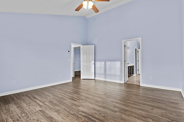 empty room with high vaulted ceiling, ceiling fan, baseboards, and dark wood-type flooring