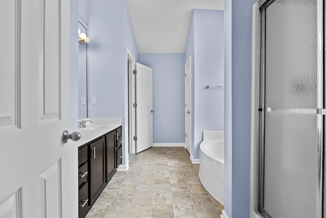 full bathroom featuring stone finish floor, vanity, a shower stall, baseboards, and a bath