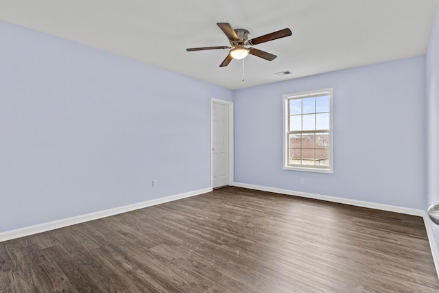 spare room featuring a ceiling fan, baseboards, visible vents, and dark wood-style flooring