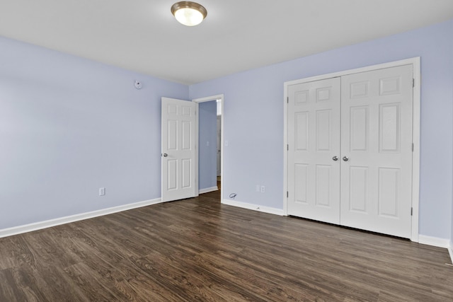 unfurnished bedroom with a closet, dark wood finished floors, and baseboards