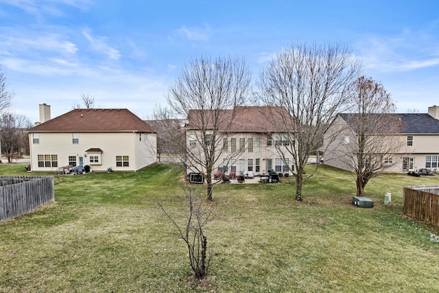 exterior space featuring a chimney, fence, a lawn, and a patio