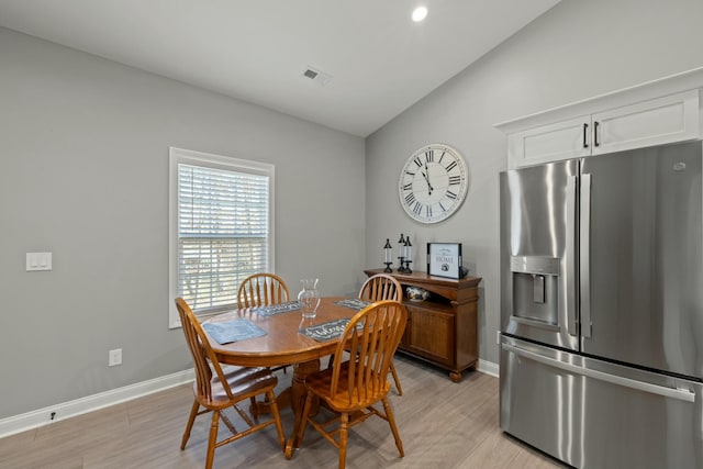 dining area featuring lofted ceiling and light wood-type flooring