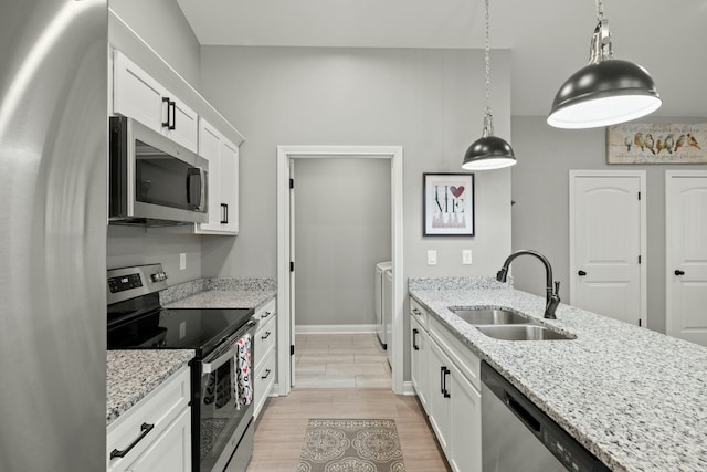 kitchen featuring sink, appliances with stainless steel finishes, white cabinetry, light stone countertops, and separate washer and dryer