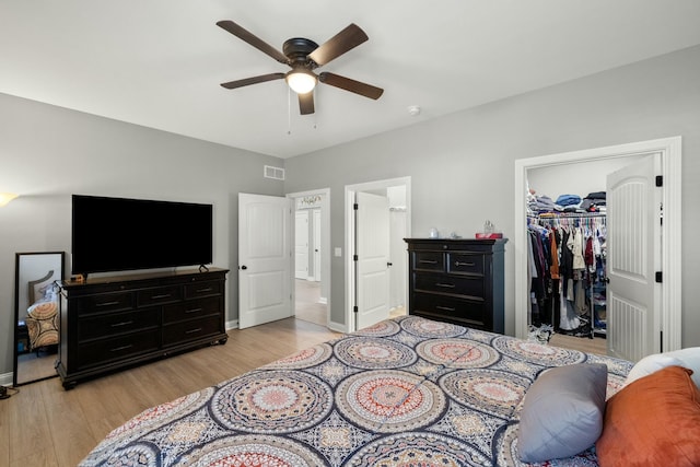 bedroom with ceiling fan, a spacious closet, light hardwood / wood-style floors, and a closet