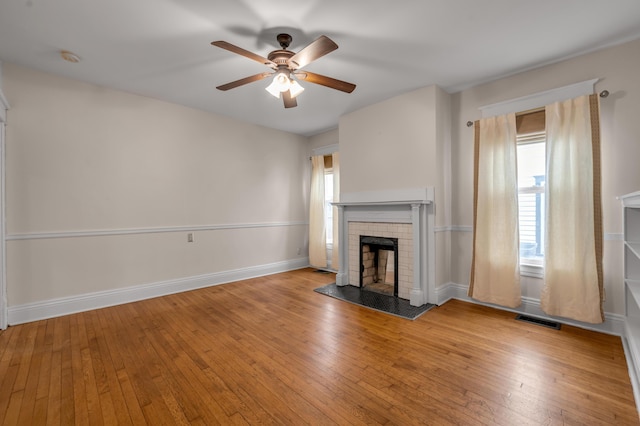 unfurnished living room with ceiling fan, a brick fireplace, and light hardwood / wood-style flooring