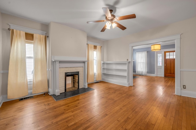 unfurnished living room featuring ceiling fan, a fireplace, and light hardwood / wood-style flooring