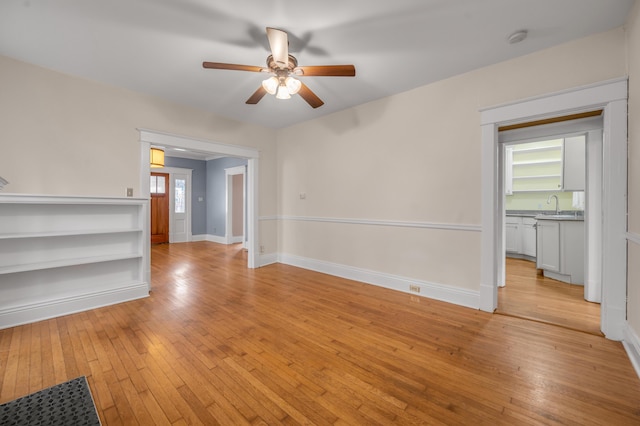 empty room with sink, light hardwood / wood-style flooring, and ceiling fan