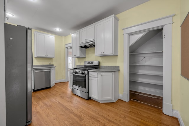 kitchen with appliances with stainless steel finishes, white cabinets, and light hardwood / wood-style flooring