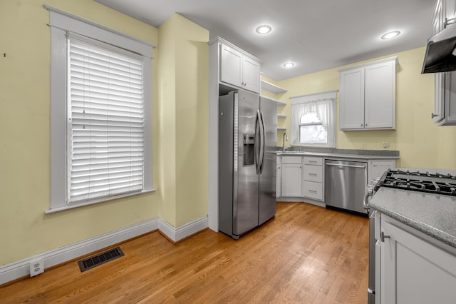 kitchen featuring appliances with stainless steel finishes, sink, light wood-type flooring, and white cabinets