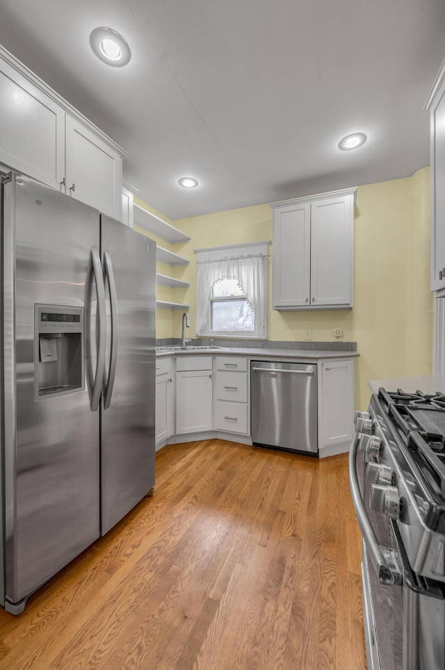 kitchen featuring white cabinetry, appliances with stainless steel finishes, sink, and light hardwood / wood-style floors