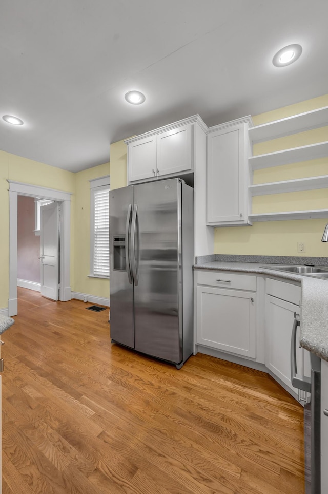 kitchen featuring white cabinetry, sink, light wood-type flooring, and stainless steel refrigerator with ice dispenser