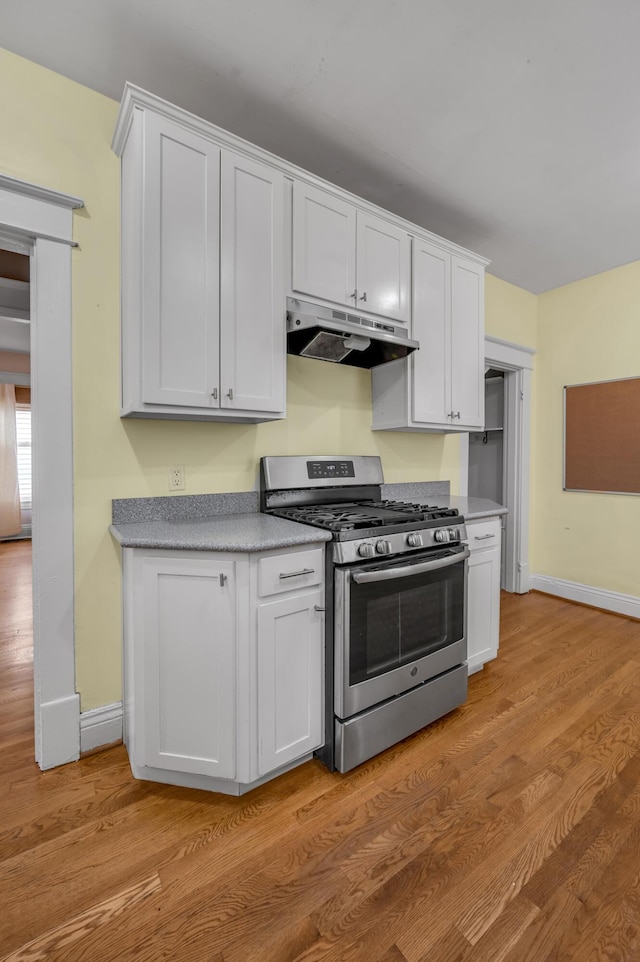 kitchen featuring stainless steel gas range, light wood-type flooring, and white cabinets