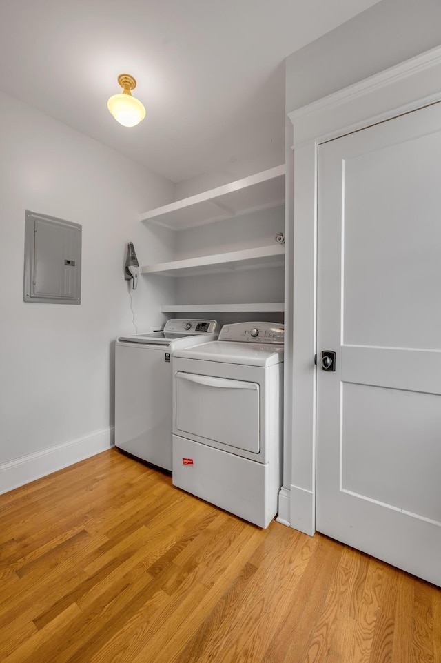 washroom featuring washing machine and clothes dryer, electric panel, and light hardwood / wood-style flooring