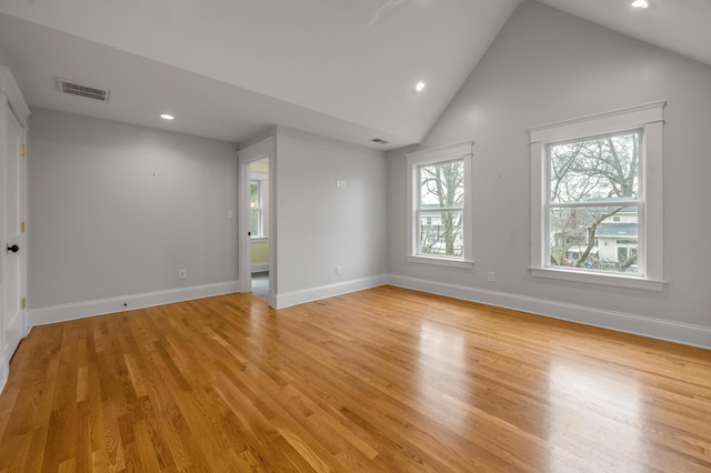 empty room with high vaulted ceiling and light hardwood / wood-style flooring