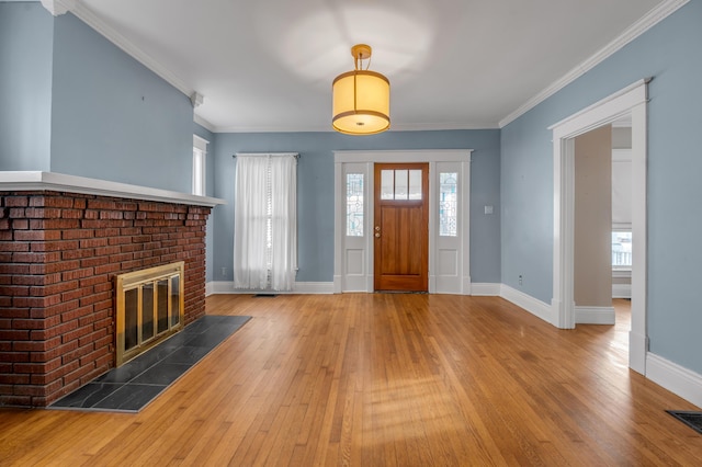 foyer entrance with hardwood / wood-style flooring, a fireplace, and ornamental molding