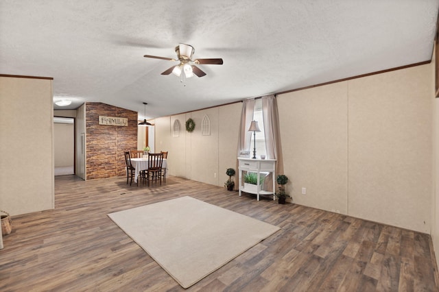 interior space with crown molding, ceiling fan, hardwood / wood-style floors, a textured ceiling, and vaulted ceiling