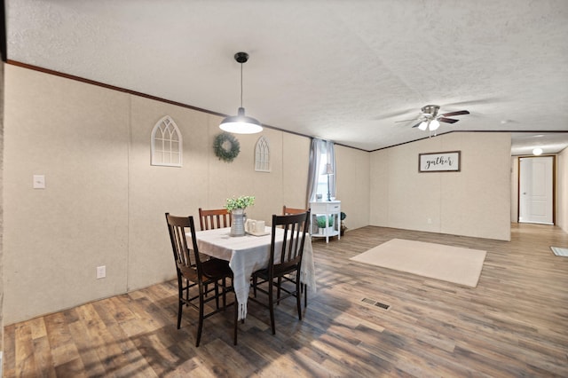 dining area with vaulted ceiling, dark hardwood / wood-style floors, a textured ceiling, and ornamental molding