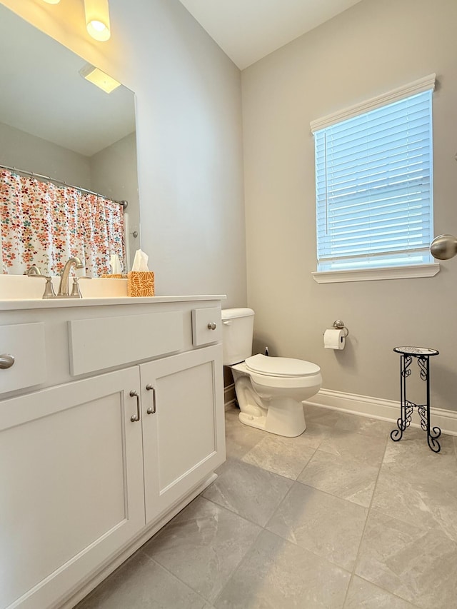 bathroom with curtained shower, toilet, vanity, and baseboards