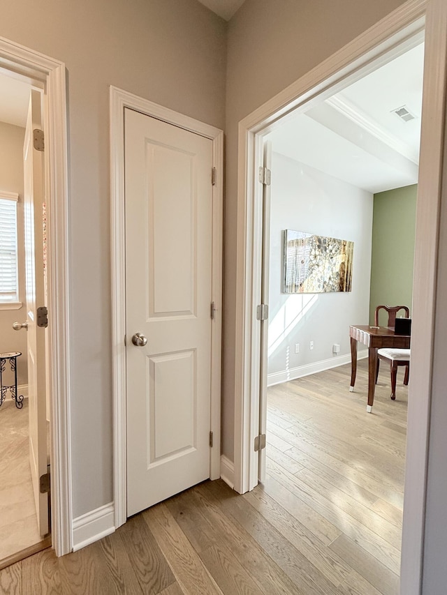 corridor featuring light wood finished floors, visible vents, and baseboards