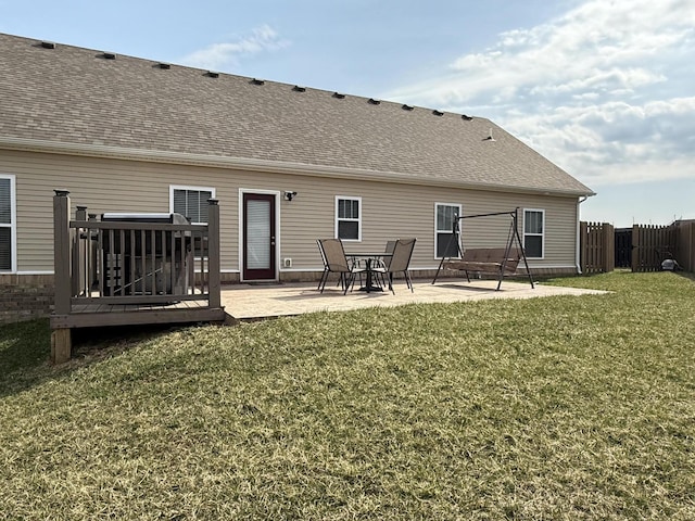 rear view of property with a patio, a yard, fence, and roof with shingles