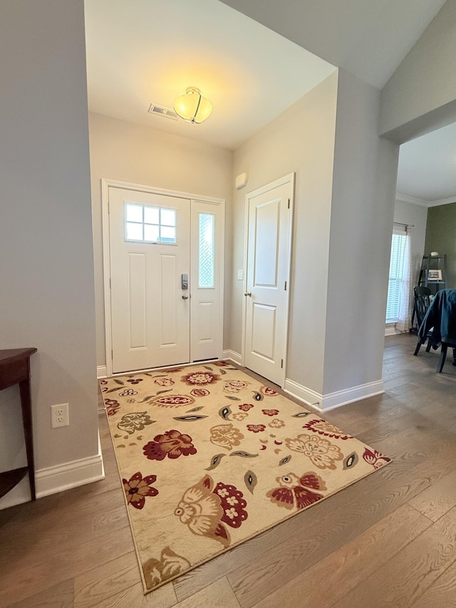 foyer featuring visible vents, baseboards, and wood finished floors