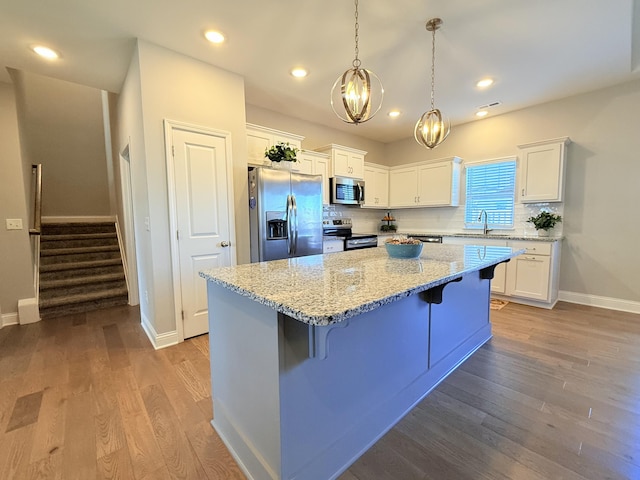 kitchen with dark wood-type flooring, a sink, backsplash, white cabinetry, and appliances with stainless steel finishes