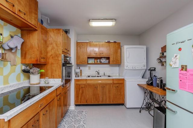 kitchen with stacked washer and dryer, sink, white refrigerator, black electric stovetop, and oven