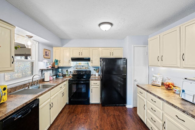 kitchen with sink, dark wood-type flooring, black appliances, a textured ceiling, and cream cabinetry