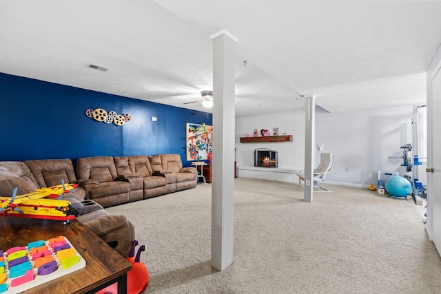 carpeted living room with ceiling fan, a fireplace, and a textured ceiling